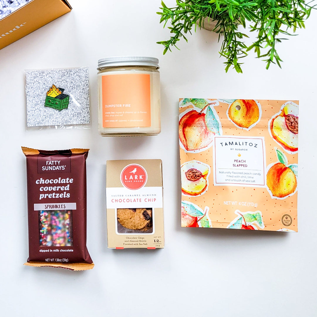 Burn It Down Gift Box – A snarky, dark-humor gift set featuring a Dumpster Fire candle, lapel pin, and sweet treats. The perfect way to cope with life’s chaos, bad days, and the state of the world.