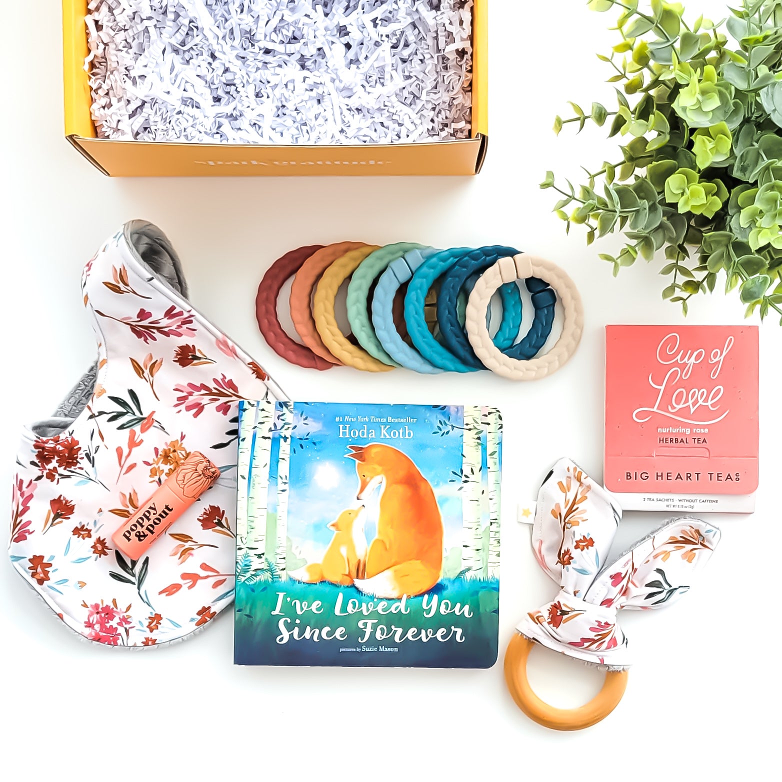 Baby Love Gift Box with a crinkle teether, multi-colored linking rings, autumn garden cloth bib, rose tea sampler, grapefruit lip balm, and optional board book—perfect for baby showers, new parents, and adoption celebrations.