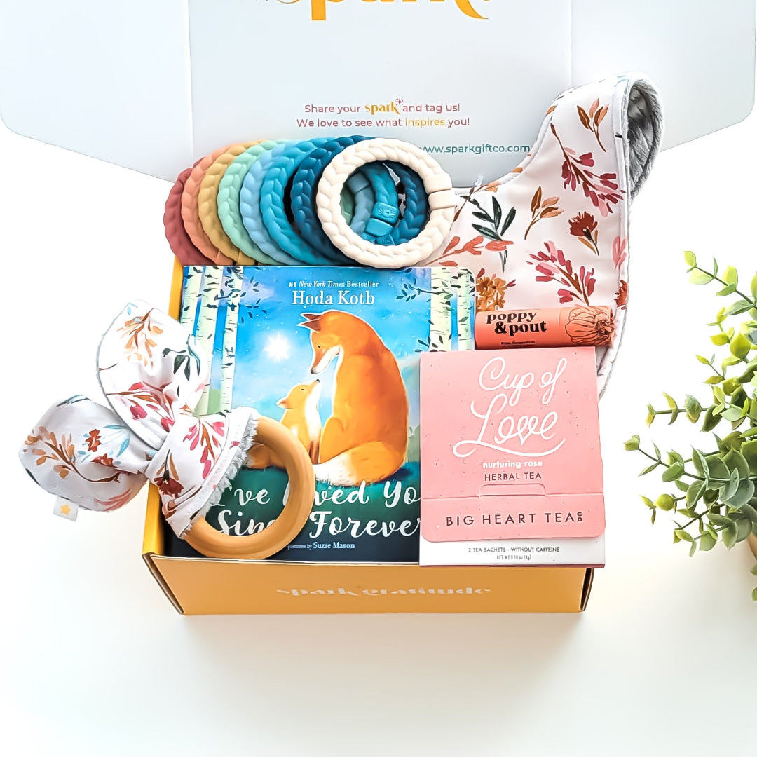 Baby Love Gift Box with a crinkle teether, multi-colored linking rings, autumn garden cloth bib, rose tea sampler, grapefruit lip balm, and optional board book—perfect for baby showers, new parents, and adoption celebrations.