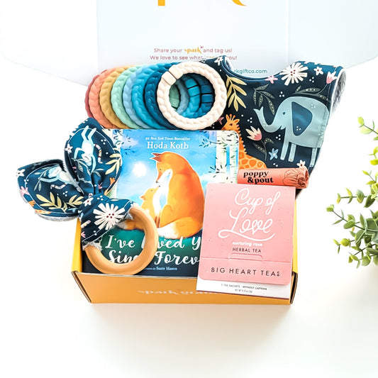 Baby Love Gift Box with a crinkle teether, multi-colored linking rings, jungle love cloth bib, rose tea sampler, grapefruit lip balm, and optional board book—perfect for baby showers, new parents, and adoption celebrations.