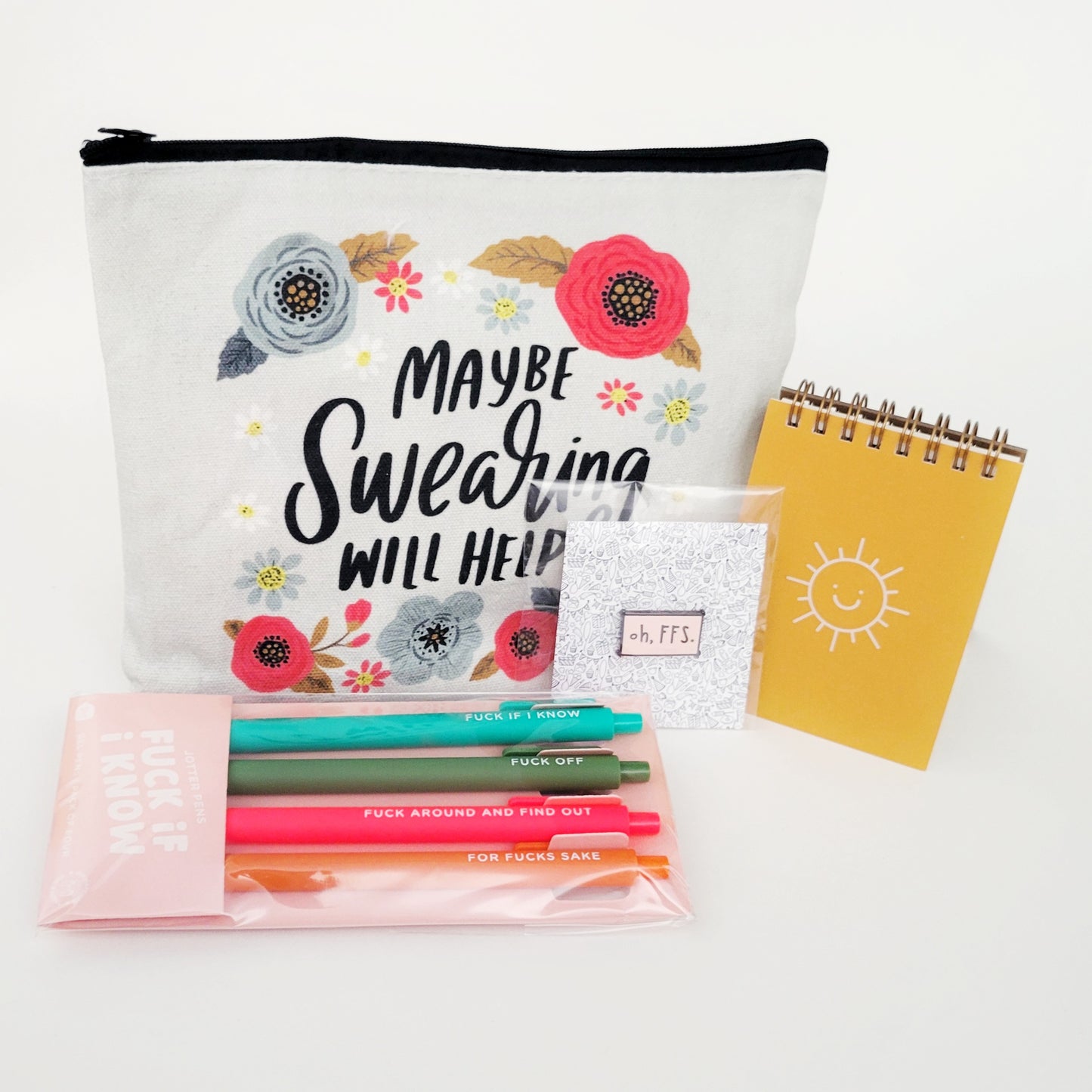 Just Gotta Swear Gift Box with a "Maybe Swearing Will Help" canvas pouch, "FFS" pin, "Fuck if I Know" jotter pen set, and Sunshine notepad—perfect for stress relief, office humor, and anyone who believes in the power of a good curse word. Ships anonymously for extra fun!