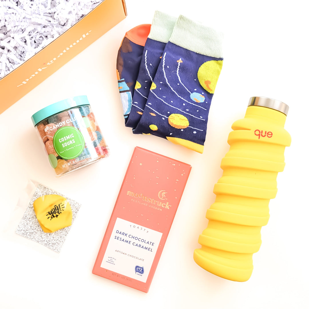 Out of This World Gift Box with space-themed socks, Moonstruck chocolate, cosmic sour candy, a collapsible water bottle, and a space balloon—perfect for galaxy lovers.